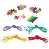 Zart Basics plastic beads and threading cords laid out on white, showing the range of bead shapes: faceted cubes, opaque and translucent pony beads, smaller round beads and longer tubes, in assorted bright colours. Four coiled nylon cords in purple, teal, yellow and red sit below.