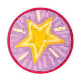 A round jigsaw sample made using a Zart Mini Jigsaw Round puzzle, hand-painted with a bold yellow star radiating light rays in shades of purple and lilac, bordered in bright pink. The puzzle piece outlines are visible across the painted design.