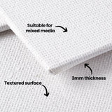 Close-up of stacked canvas boards showing the canvas weave and layered edge construction. Black annotation text and arrows point to features on the board, reading Suitable for mixed media, 3mm thickness, and Textured surface.