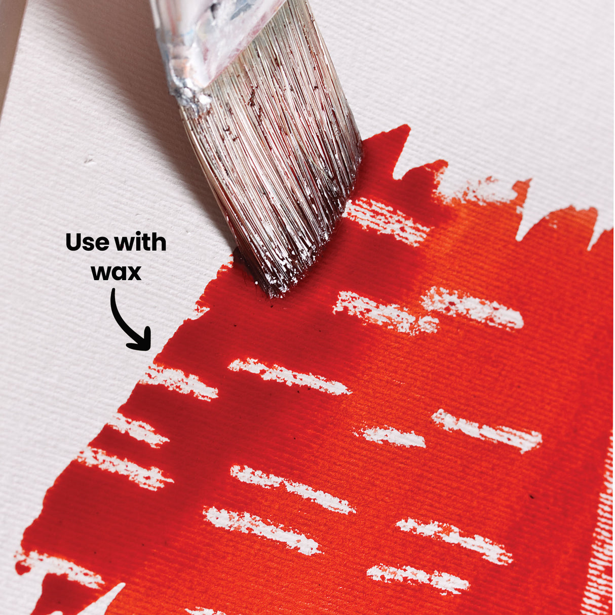 An annotated close-up of a red-orange watercolour wash painted over a wax-resist pattern of horizontal lines, using Eco Colour Liquid Food Dyes, with a paintbrush shown applying the colour. Labelled "Use with wax", demonstrating how wax resist creates a striped, textured effect.