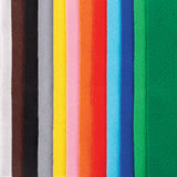 A close-up of Zart felt sheets standing edge to edge, showing the colour range side by side: white, brown, black, grey, yellow, pink, orange, red, sky blue, navy and two shades of green. Each sheet has a soft, matte, slightly fuzzy texture typical of felt.