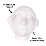 White sculptural head form created with Paper Magiclay, featuring smooth surface details including facial features, ears, and hair. Text annotations point out "No adhesives needed" at the top and "Paper-like texture once dry" at the base, demonstrating the clay's self-adhesive properties and finished texture.