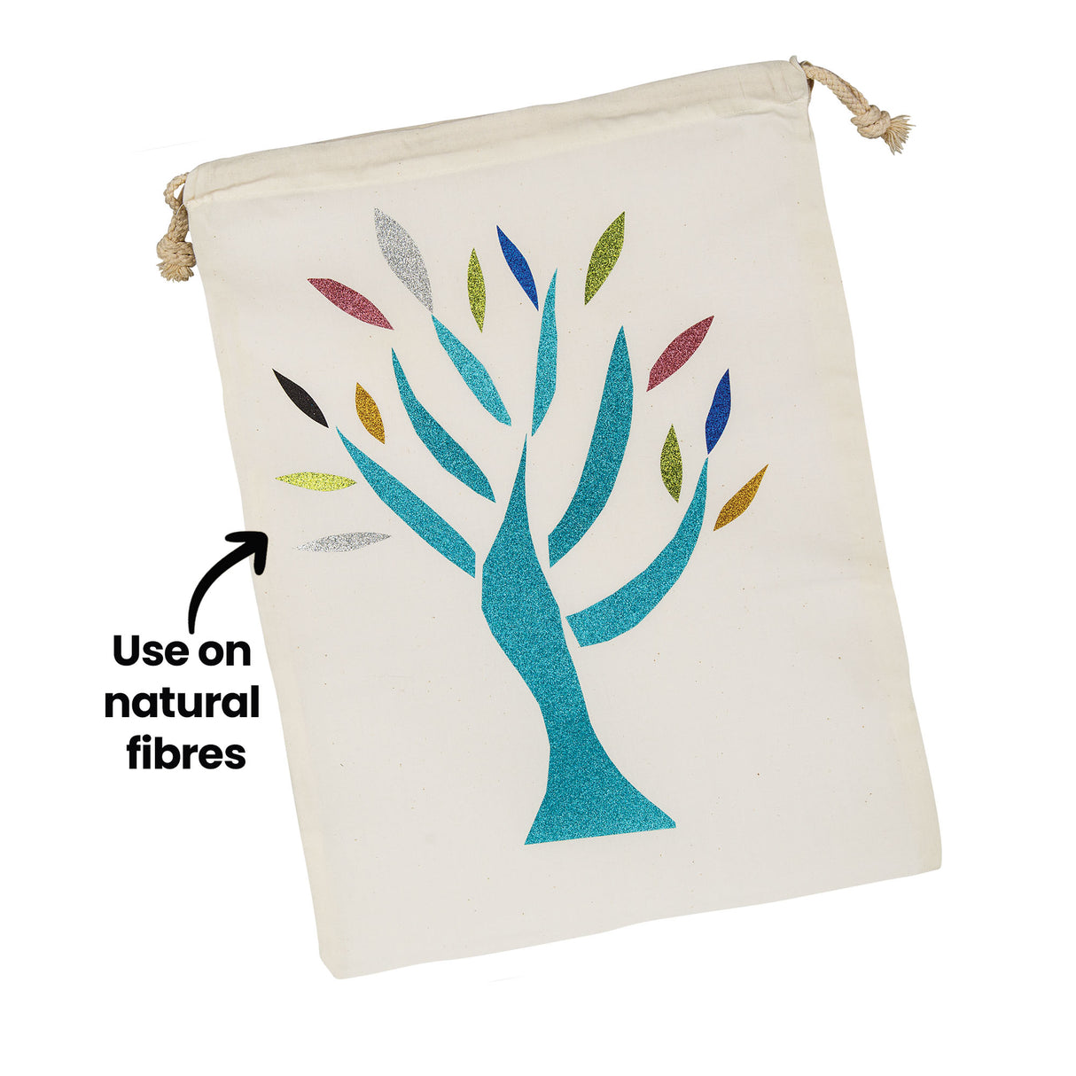 A cream cotton drawstring bag decorated with a glittering tree design in teal, with leaves in silver, gold, blue, green and pink Zart Glitter Iron-On Sheets. The annotation 'Use on natural fibres' points to a leaf, indicating the fabric type suited to application.