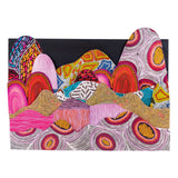 A layered landscape collage built from Zart Pattern Paper, with overlapping hill and mountain shapes cut from different patterned sheets. Dot-work circles, wavy lines, concentric ovals and bold colour blocks in pink, orange, teal and gold rise against a black background, forming a vibrant scenic composition.