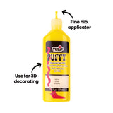 A yellow Tulip Puffy Dimensional Fabric Paint bottle with a red nozzle cap, annotated with black arrows and text reading “Fine nib applicator” pointing to the narrow pointed tip, and “Use for 3D decorating” pointing to the raised puffy paint design on the label.