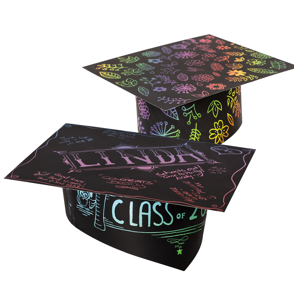 Two decorated Scratch Graduation Hats. The rear hat is covered in rainbow flowers and leaves scratched from the black surface. The front hat shows the scratched name "LINDA", "CLASS of", an owl and handwritten messages in pink, blue and green.