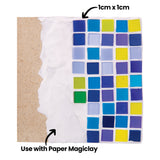 A grid of blue, purple, green and yellow Zart Deco tiles pressed into white clay over a brown board, with annotations "1cm x 1cm" pointing to a single tile and "Use with Paper Magiclay" pointing to the clay base. The glossy squares sit in neat rows.