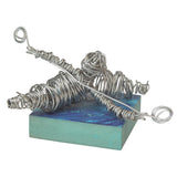 Finished abstract sculpture created from Armature Wire, tightly coiled and wrapped to form a reclining figure mounted on a painted rectangular base. The silver wire construction showcases strength, structure and suitability for three-dimensional modelling.