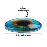 Circular resin Creature Eye with domed surface showing swirling blue, green, orange and black marbled colours. Annotation text reads 0.5cm dome height and 2.5cm diameter, indicating the eye's dimensions and raised profile against a white background.