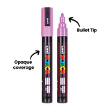 Two Uni POSCA pastel paint markers standing upright, one capped and one uncapped to show the purple bullet tip. Text highlights the marker’s bullet tip and opaque coverage.
