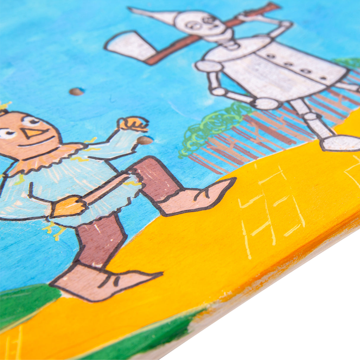 Close-up of a painted skateboard deck illustrating hand-drawn characters and scenery, showing markers, line detail and mixed media application on the plywood surface.
