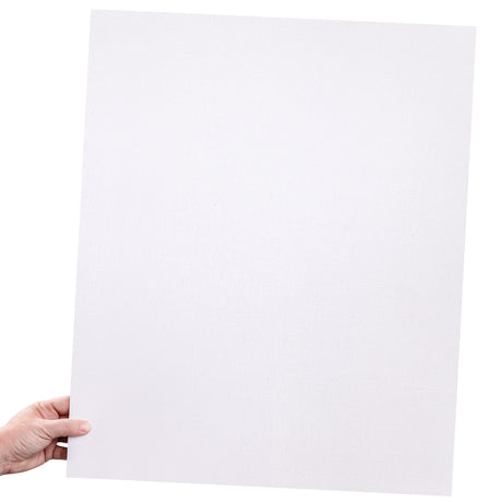 A hand holds a large rectangular canvas board against a light neutral background. The board has a white primed surface with a visible fine canvas weave. The edges appear thin and firm, showing the rigid backing typical of a canvas board.