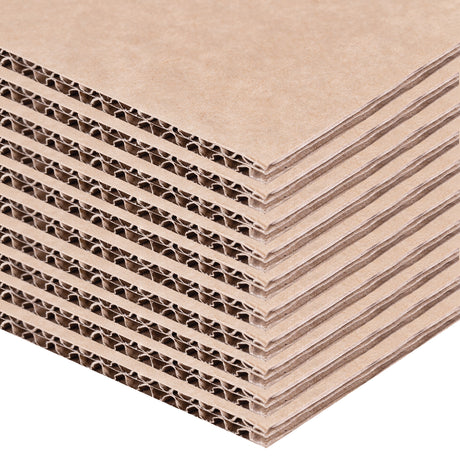 A close-up stack of brown Backdrop Card sheets is shown layered diagonally against a pale background. The exposed corrugated edges reveal repeating fluted cardboard channels, while the smooth kraft paper surfaces display natural fibre texture and sturdy construction suitable for model making and display projects.