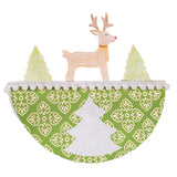 A hand-decorated Zart Rocking Christmas Card featuring a pencil-drawn reindeer with a red nose standing between two green trees, all coloured in soft pastel shading. The lower half shows a green foiled pattern with a white pom-pom trim and a plain white tree cut-out.
