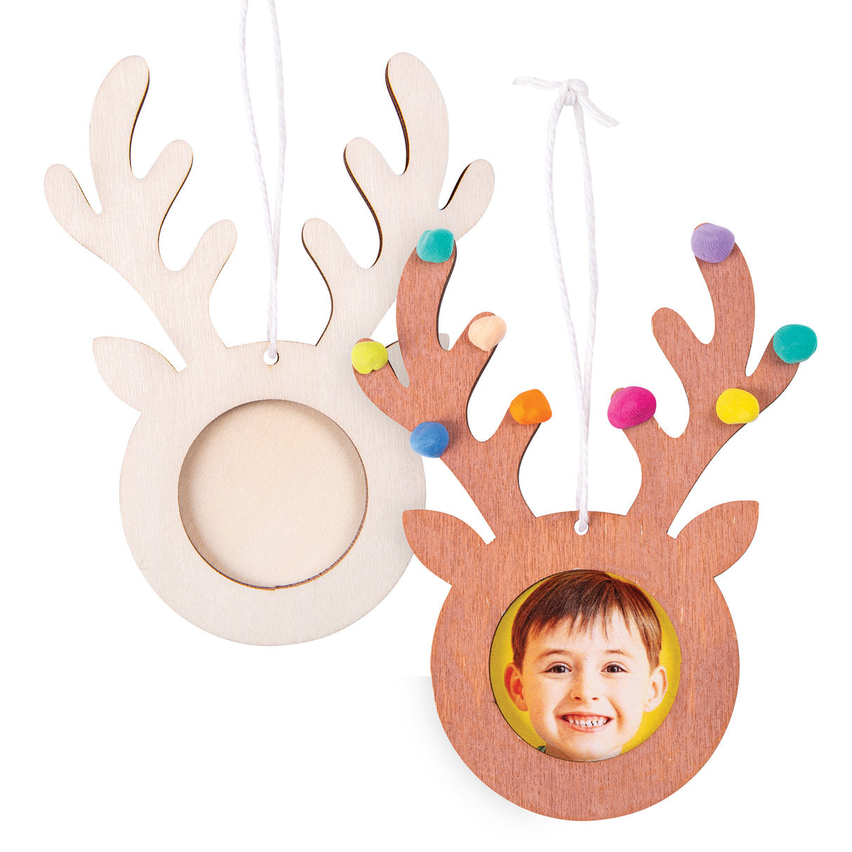 Wooden reindeer-shaped frames with antlers and white hanging cords, shown in natural wood. One decorated example features a child's photo in the circular frame opening with colourful pom-poms adorning the antlers in yellow, pink, orange, blue, purple and teal, creating a festive Christmas ornament.