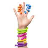 Child's hand wearing colourful textured sensory fidget toys including spiral orange and blue finger twists, and various wrist bands in lime green with spiky texture, hot pink with beaded segments, yellow with rope texture, and purple smooth twist design from the Sensory Sprouts Textured Twistable Strings Set of 6.