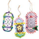 Three decorated Zart Wooden Lantern Frames hang side by side on jute string. The left is painted purple and green with silver and green gem clusters; the centre features a pink and blue onion-dome shape with a yellow star and sequins; the right shows red-and-white stripes with a silver embossed medallion and holly.