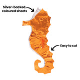 An embossed copper-toned Aluminium Embossing Foil Sheet shaped like a seahorse displays a crinkled reflective surface with visible indentations and highlights. Black annotation text reads “Silver-backed coloured sheets” and “Easy to cut” with arrows pointing to the material and cut edge.