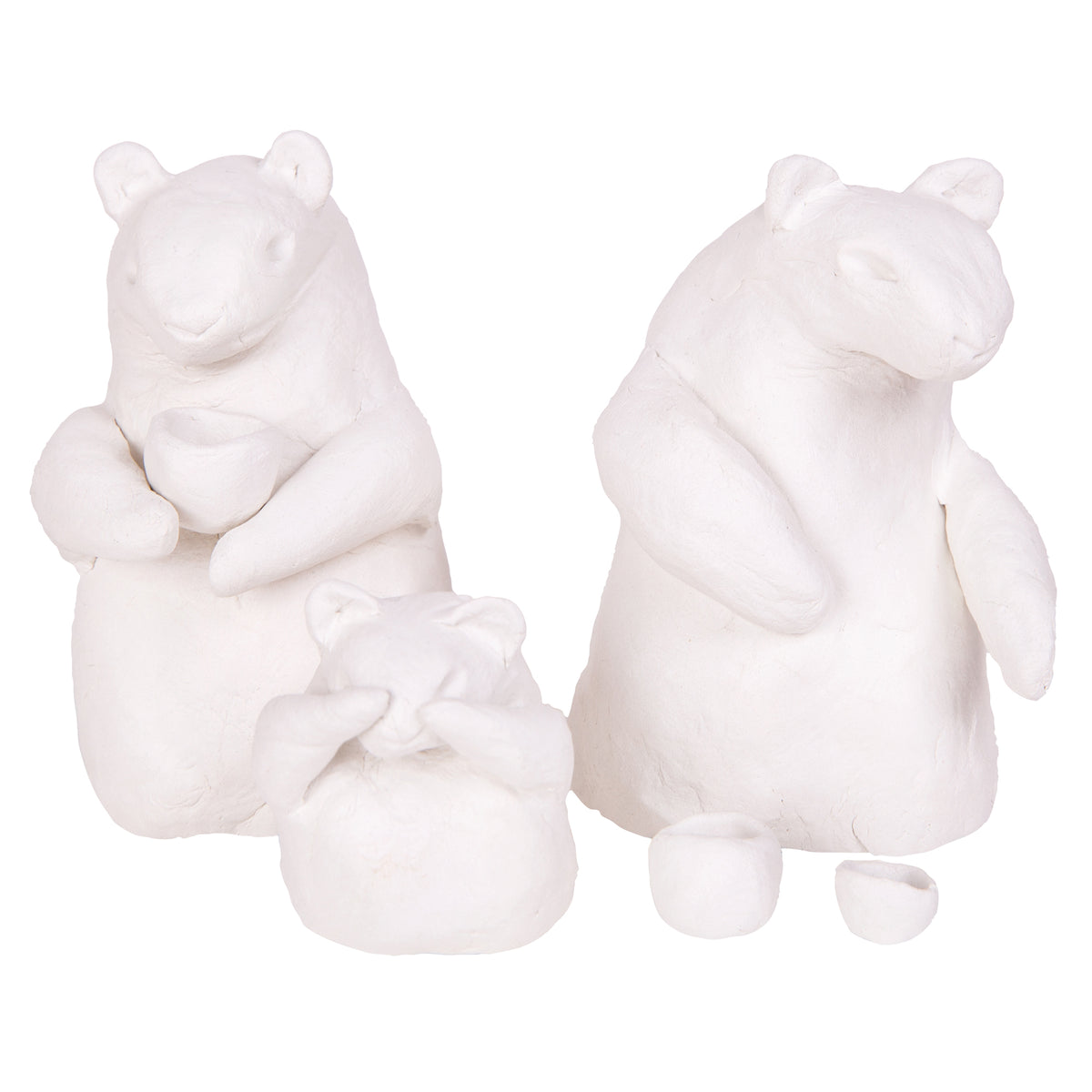 Three unpainted white clay figures shaped like bears, each with rounded ears and bodies, two holding small cup-like shapes. Additional tiny cup and bowl pieces sit on the ground beside them, showing the smooth workable finish of the clay.