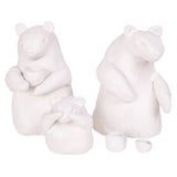 Three unpainted white clay figures shaped like bears, each with rounded ears and bodies, two holding small cup-like shapes. Additional tiny cup and bowl pieces sit on the ground beside them, showing the smooth workable finish of the clay.