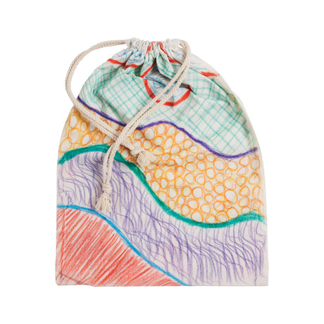 Natural calico drawstring bag decorated with colourful marker designs. Wavy bands, crosshatching, and circular patterns in orange, green, purple, and red cover the surface. The soft fabric shows creases beneath the artwork, with cream cords loosely tied at the top.