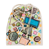 Decorated calico drawstring bag featuring bold geometric shapes in bright colours. Circles, triangles, and rectangles outlined in black are filled with neon pink, blue, green, and orange. The fabric texture remains visible beneath the layered marker and pastel application.