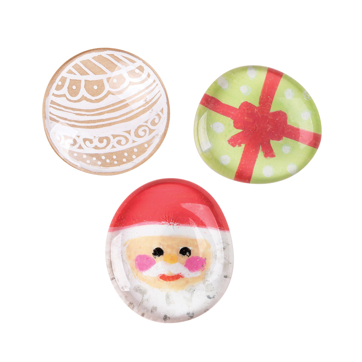 Three Zart Glass Stones with a smooth domed clear surface, each backed with a different festive print: a swirled gingerbread-style ornament in tan and white, a green polka-dot gift wrapped in a red ribbon bow, and a red-hatted Santa face with rosy cheeks.