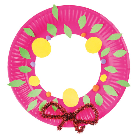 Zart Paper Plates crafted into a Christmas wreath, with a hot pink plate ring decorated with green paper leaves, yellow paper circle baubles, and small orange and purple pom-poms. Finished with a red and gold tinsel bow at the base, made from twisted glittery pipe cleaner-style trims.
