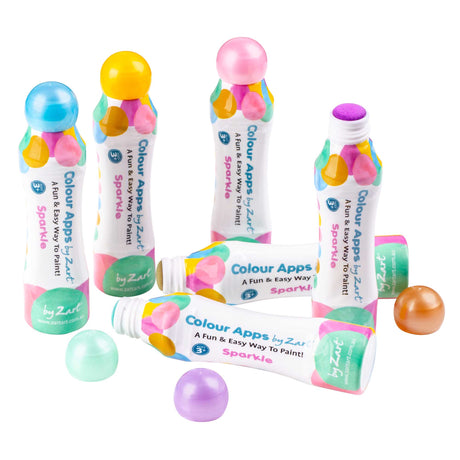 Assorted Zart Colour Apps Sparkle bottles arranged on a white background. Bottles stand and lie flat, showing pastel-coloured caps, patterned labels and loose caps revealing sponge applicators.
