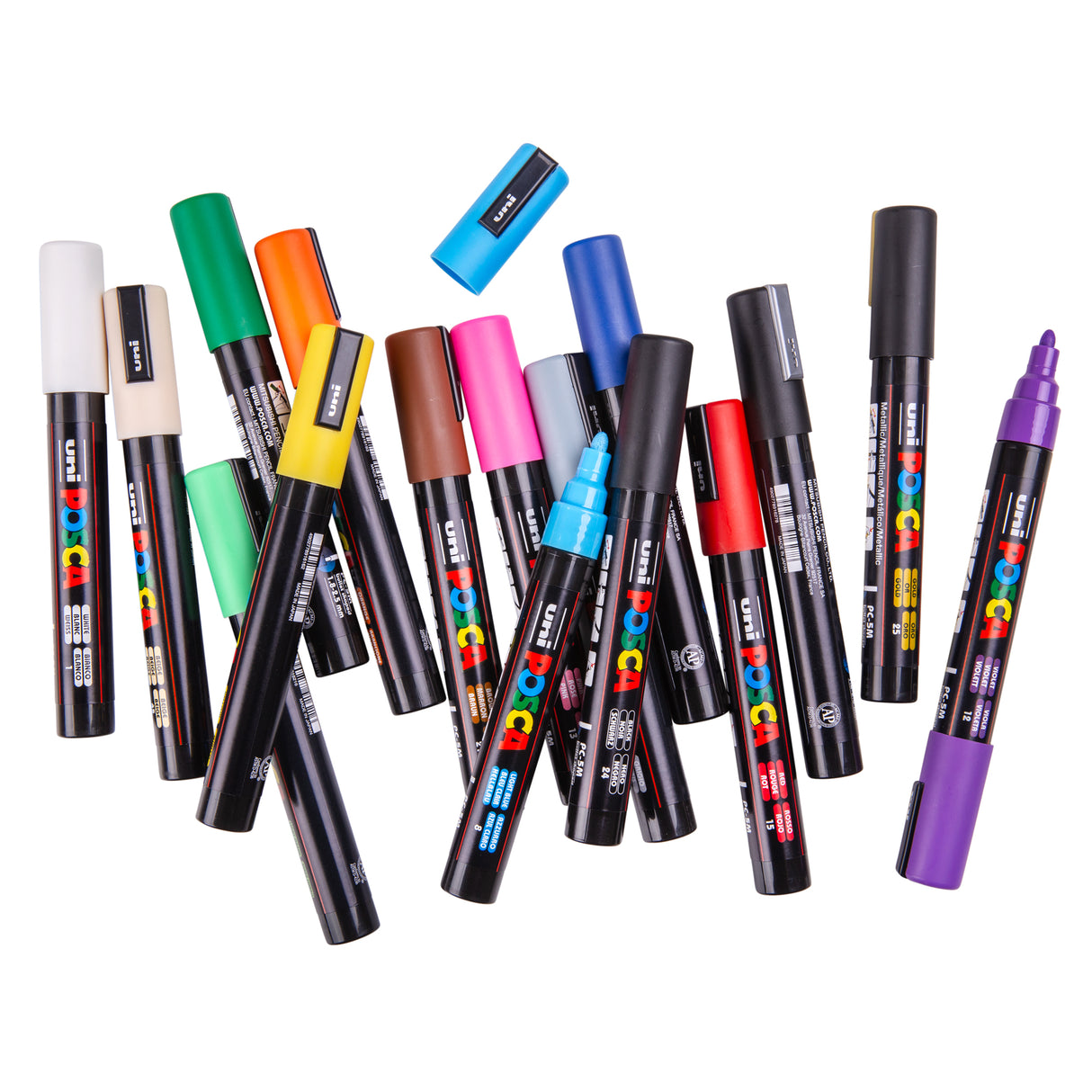 A selection of Uni POSCA paint markers scattered on a white background, showing a variety of colours and some uncapped markers with visible nibs.