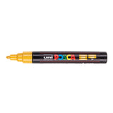 A uni POSCA paint marker shown horizontally against a white background. The glossy black cylindrical barrel carries the colourful POSCA branding and is topped by a uni clip, with the coloured cap or exposed bullet nib indicating the paint colour inside.