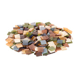 A rounded pile of Zart Deco mosaic tiles in the earth colour range. The small squares blend browns, creams, tan, moss green, grey and soft blue, mixing glossy and frosted finishes. Piled together, the muted, natural palette shows warm and cool earthy tones across the heap.