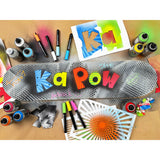 Decorated skateboard deck surrounded by spray paints, markers and stencil sheets. The deck features bold graffiti-style lettering reading “Ka Pow”, with handwritten tags layered over stencilled dots and textures.