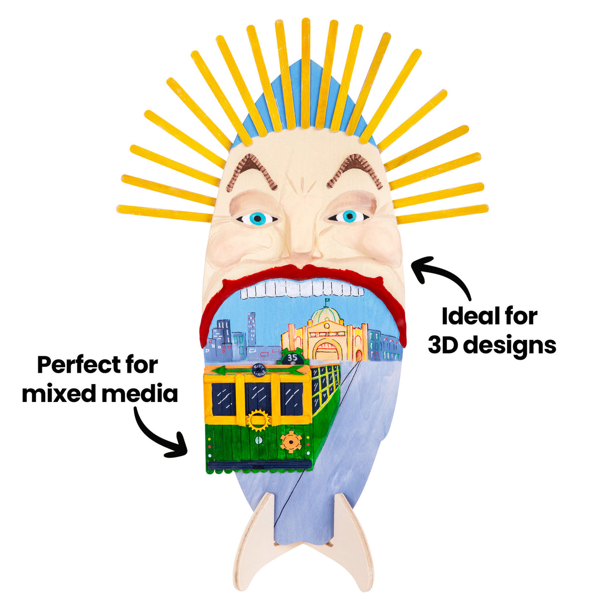 Painted wooden surfboard artwork on a stand featuring a large stylised face with an open mouth and a tram emerging, city scene inside. Annotation text reads “Perfect for mixed media” and “Ideal for 3D designs”.
